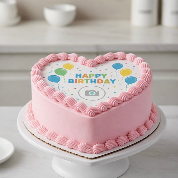 Heart-shaped birthday cake with pink frosting and 'Happy Birthday' text on a white surface.